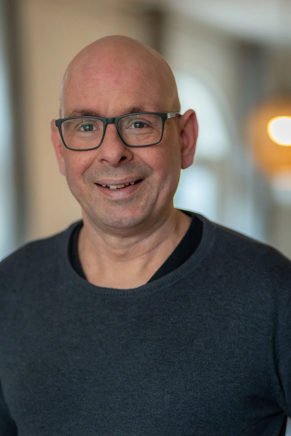 Portret van Roeland, lachend, in een grijze trui.